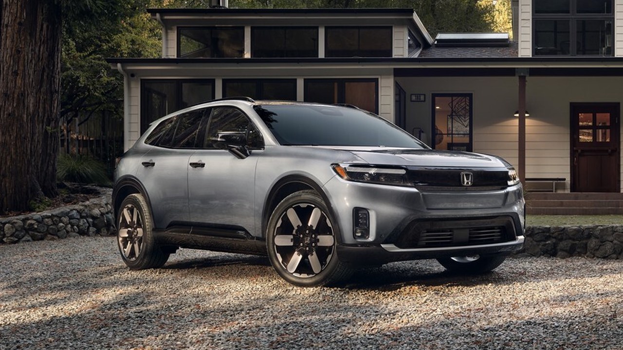 A grey Honda Prologue parked outside of a house in a wooded area
