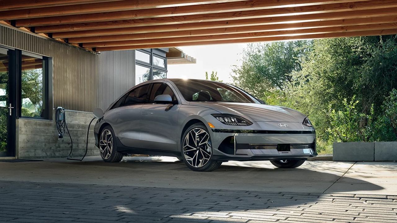 A grey Hyundai Ioniq6 under a carport plugged into an EV charger