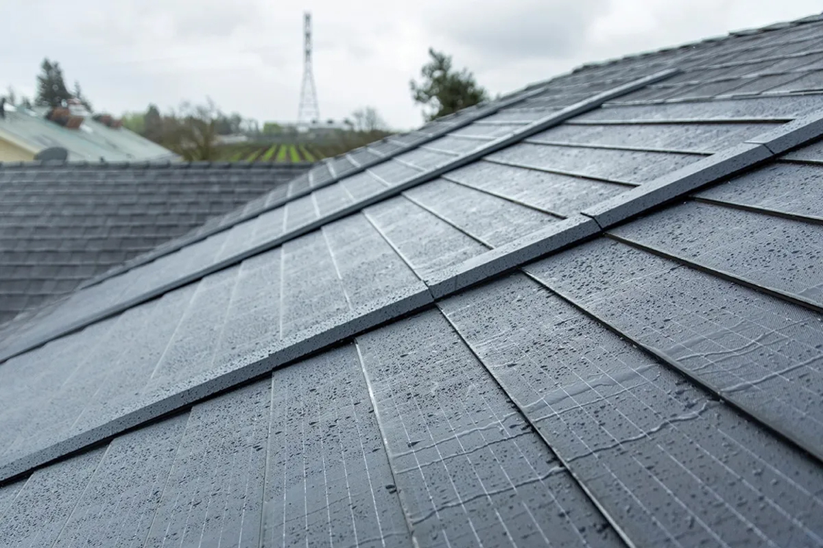 A close up view of GAF Energy's Timberline solar shingles with rain falling down them.