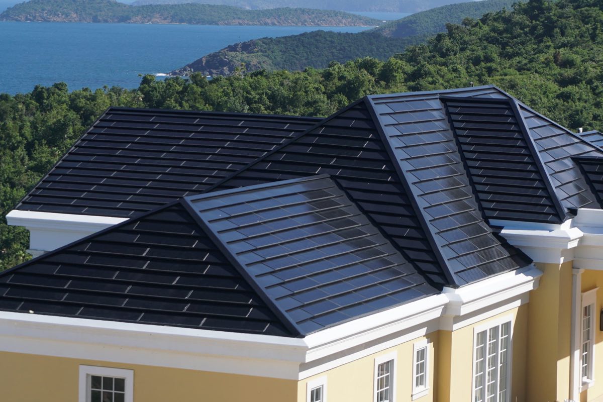 View of a home's roof with Luma Solar Shingles installed with a mountain and lake in the background.